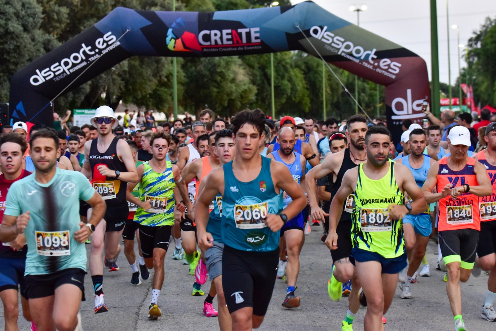 A large pack of runners sprints beneath the start arch at the XI Nocturna del Alamillo in Sevilla