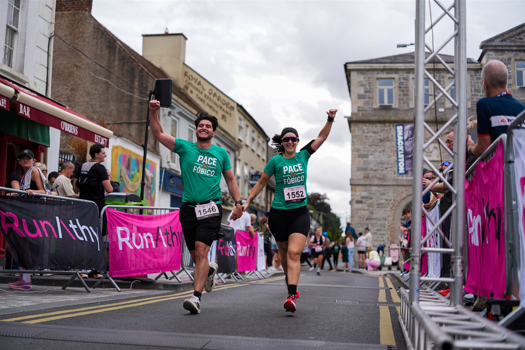 Two runners hold hands and raise their arms as they cross the finish line at the 2026 Athy Half Marathon