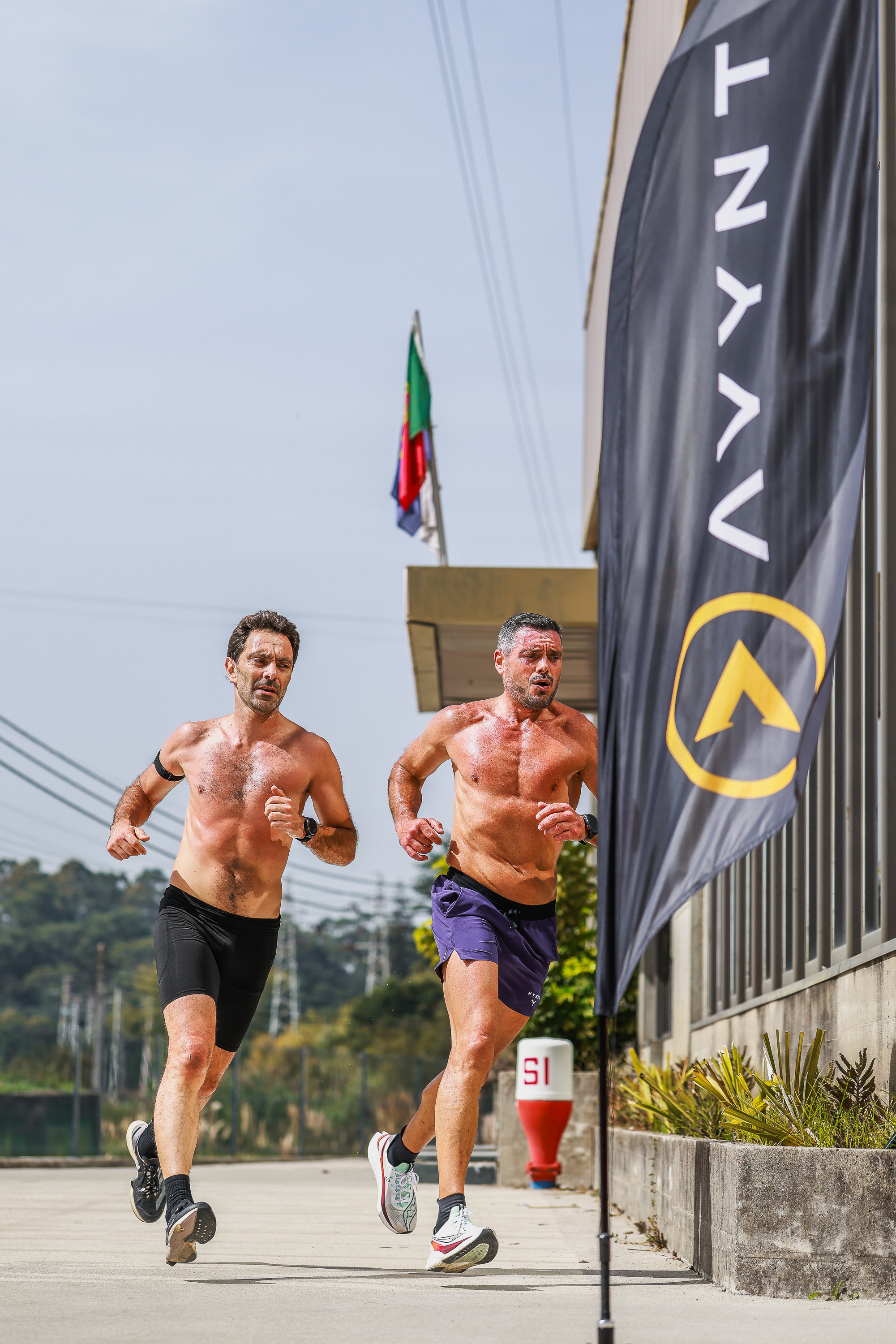 Two athletes run beside AVYNT signage in Vila Nova de Gaia