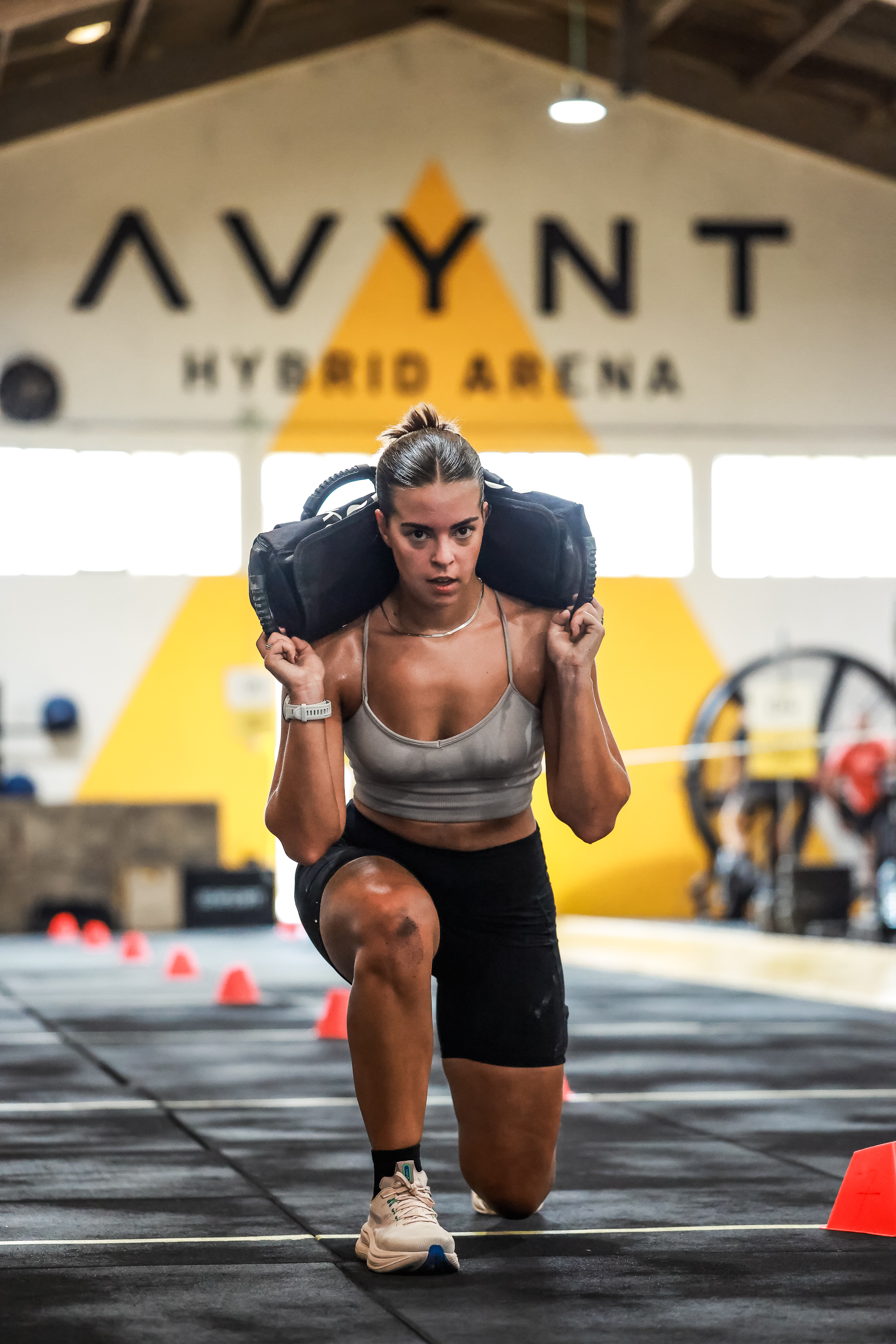 Athlete performs a sandbag lunge inside AVYNT Hybrid Arena