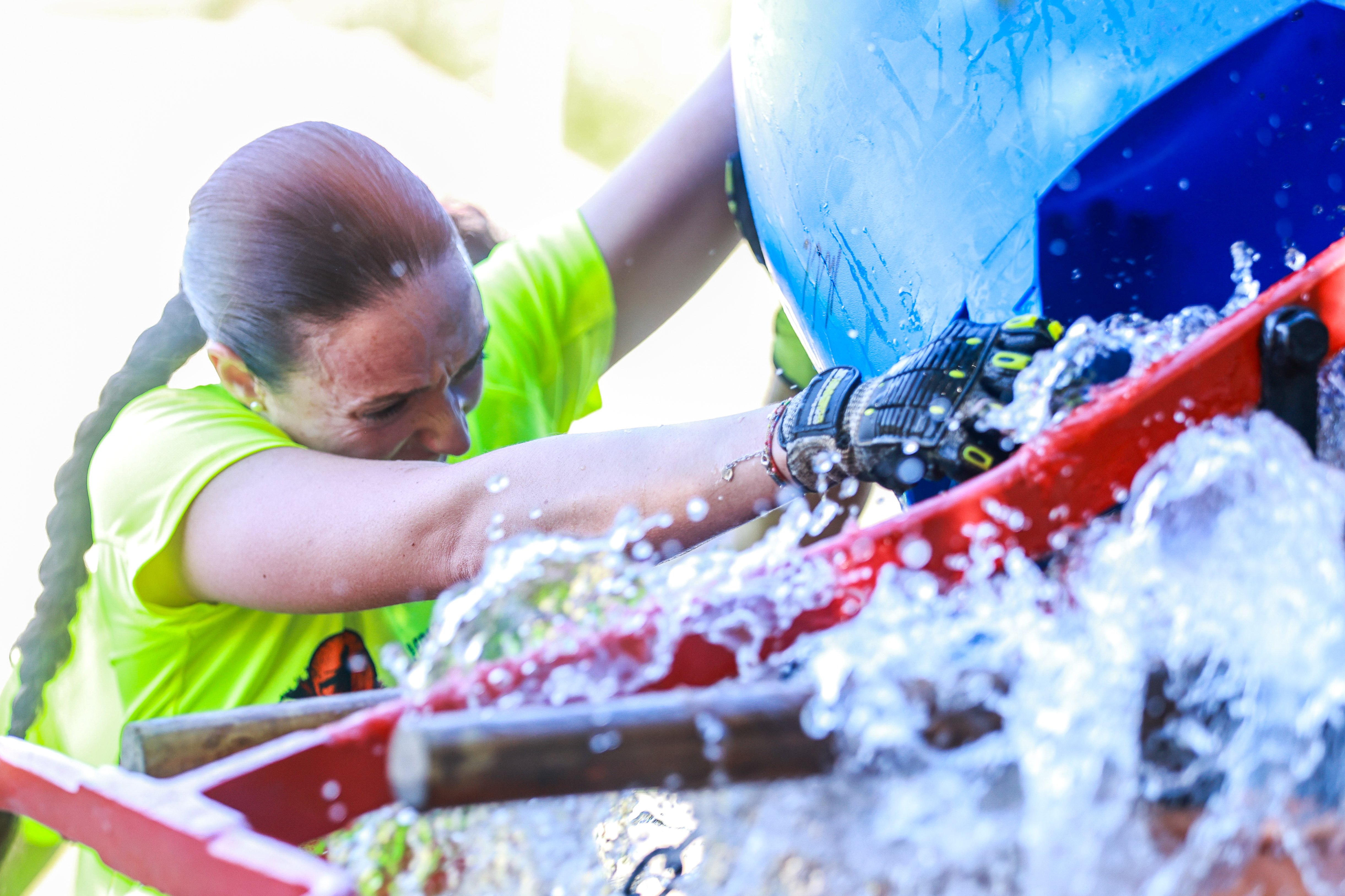 A competitor tackles an obstacle amid splashing water
