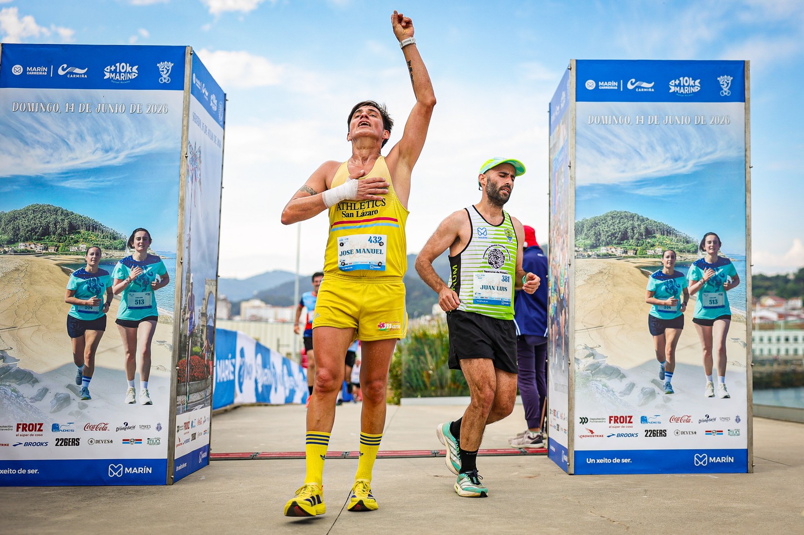 A runner raises a fist while crossing the finish line at the V Carmiña Carreira in Marín