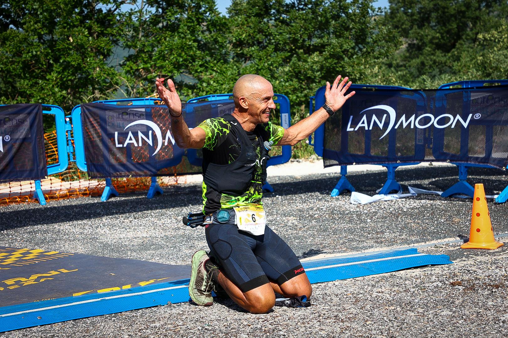 A finisher kneels and raises his arms in celebration after crossing the line at Chandrexa Trail 2026 in Chandrexa de Queixa