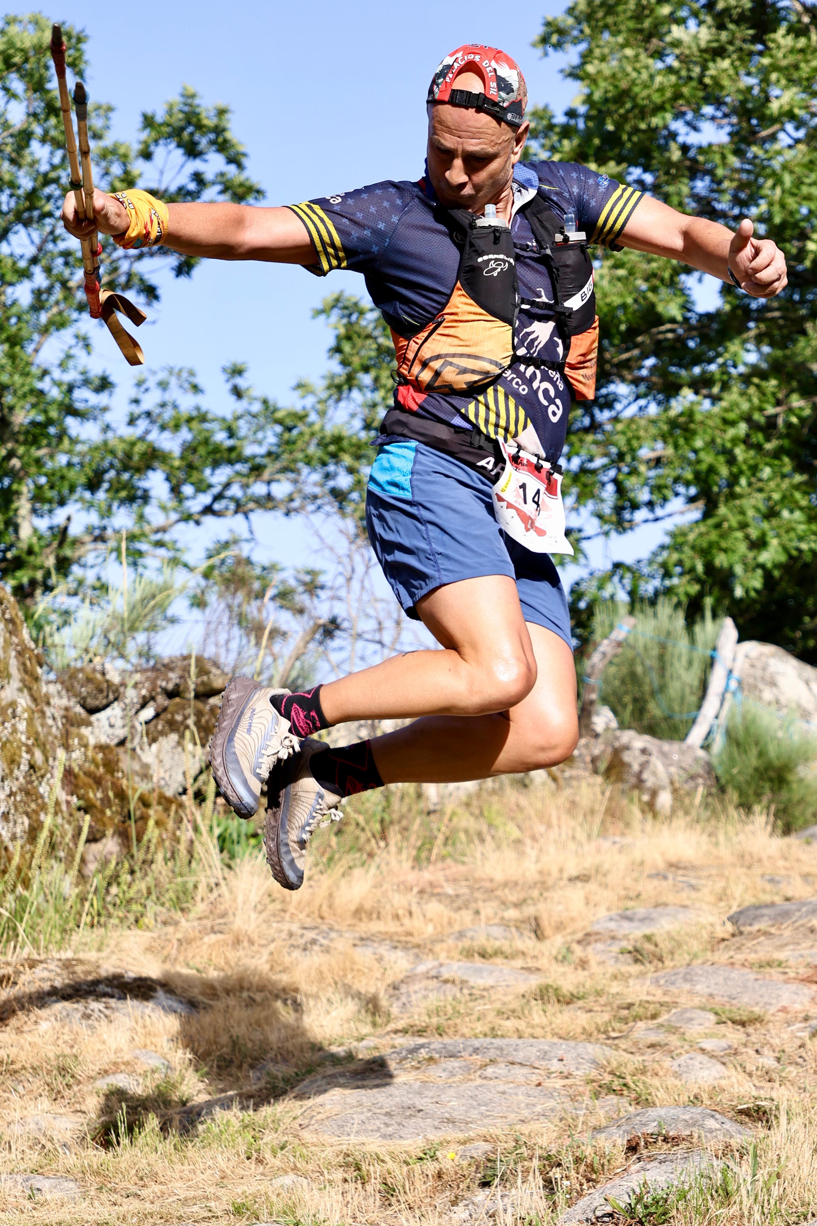 A competitor uses trekking poles to jump over rocky terrain during Chandrexa Trail 2026