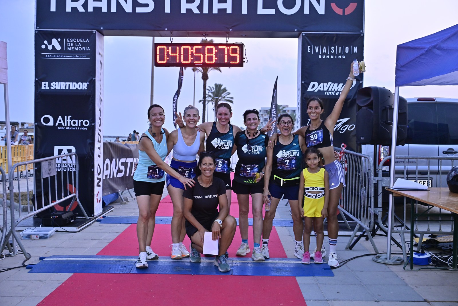 Women’s competitors celebrate together beneath the Transtriatlón finish arch after the inaugural Cunit Night Race