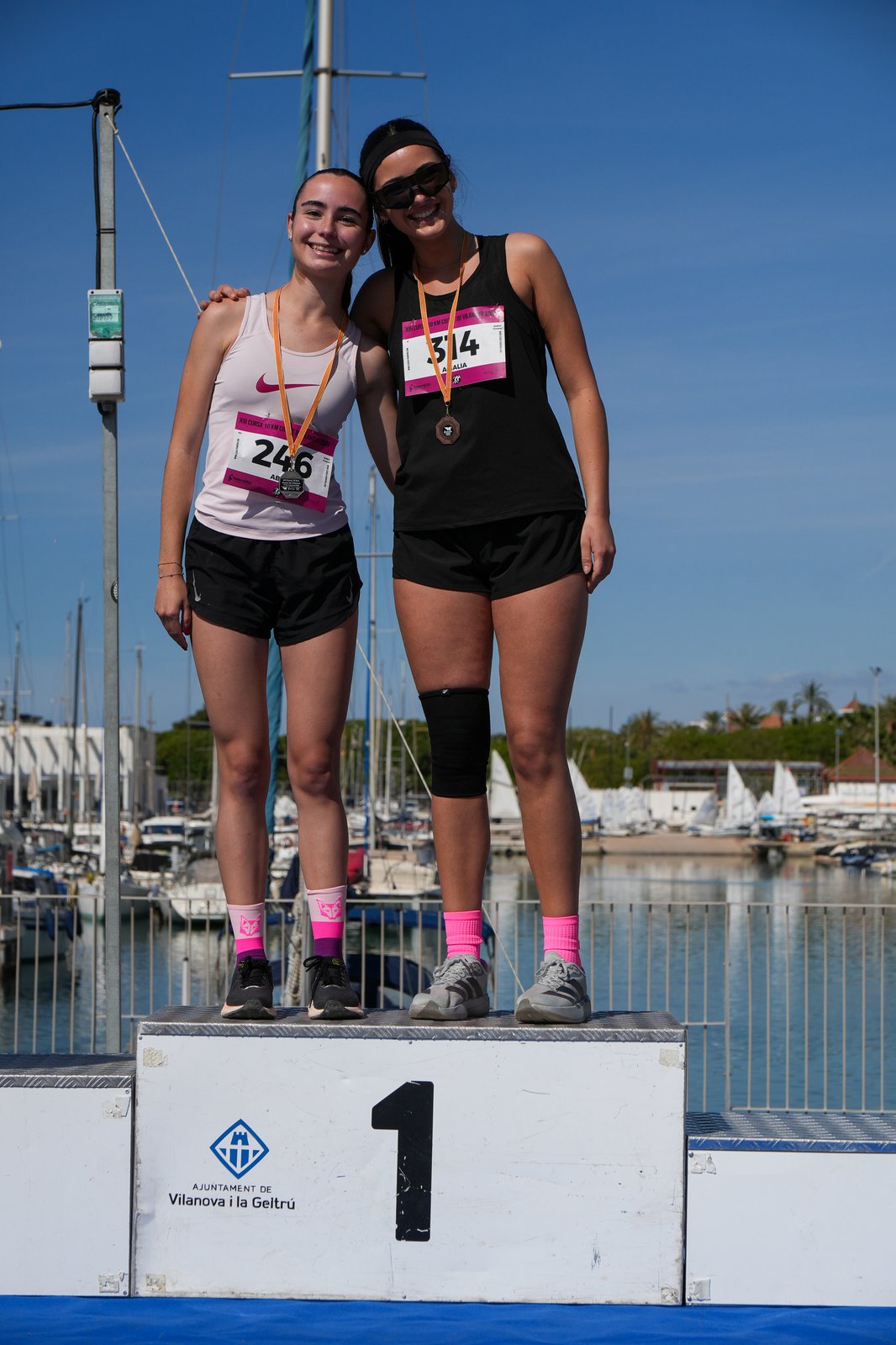 Two runners celebrate on the awards podium at the Cursa Ciutat de Vilanova