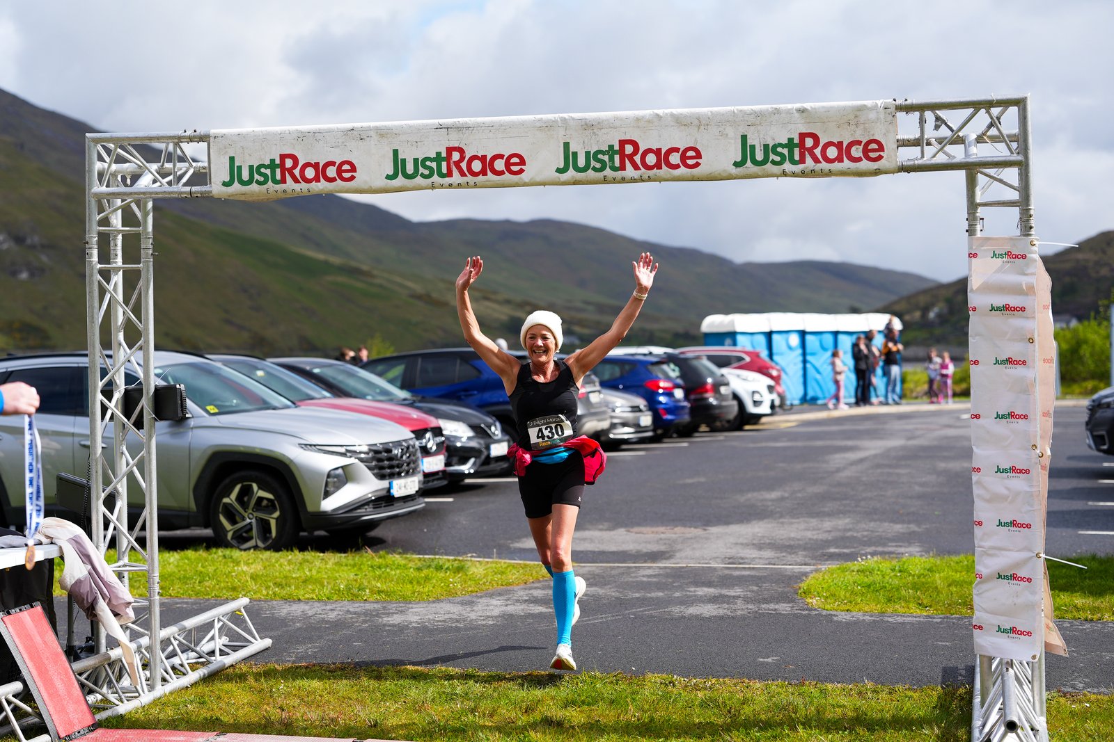 A runner celebrates with arms raised crossing the finish line at the Delphi Half Marathon & 10K
