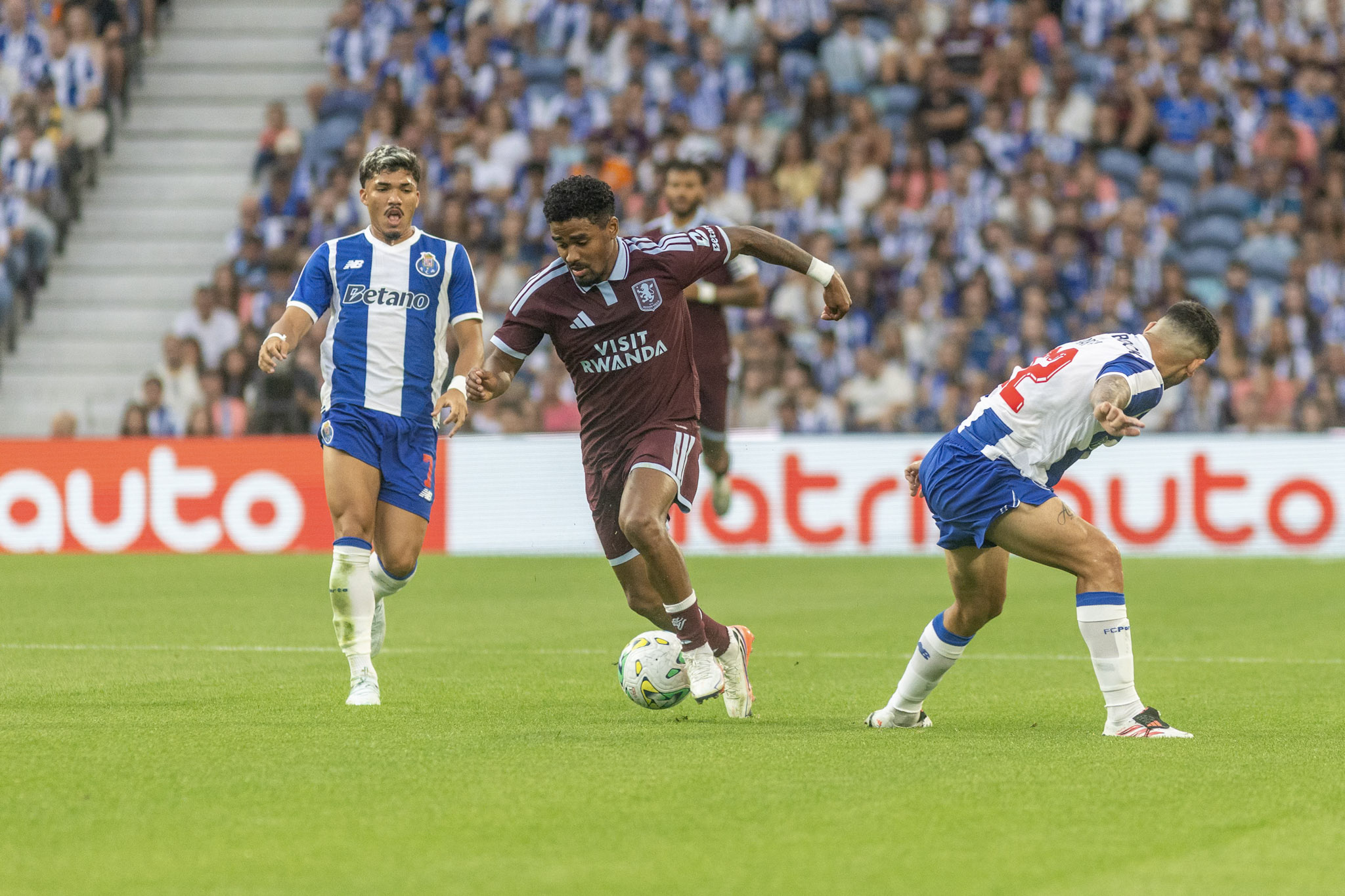 An Aston Villa player carries the ball between FC Porto players during the pre-season friendly at Estádio do Dragão