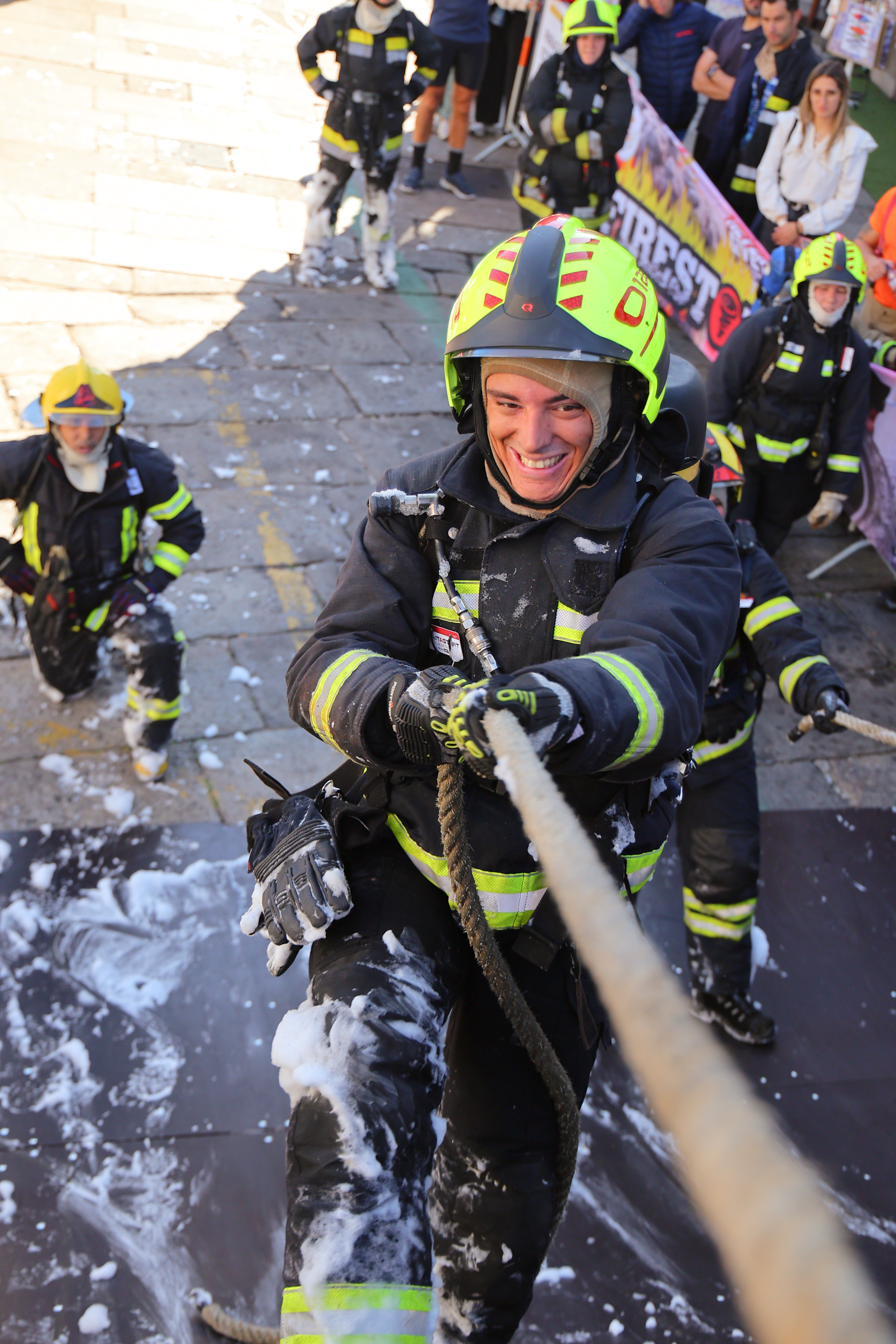 A firefighter climbs a rope through foam during Firestorm Challenge 2026