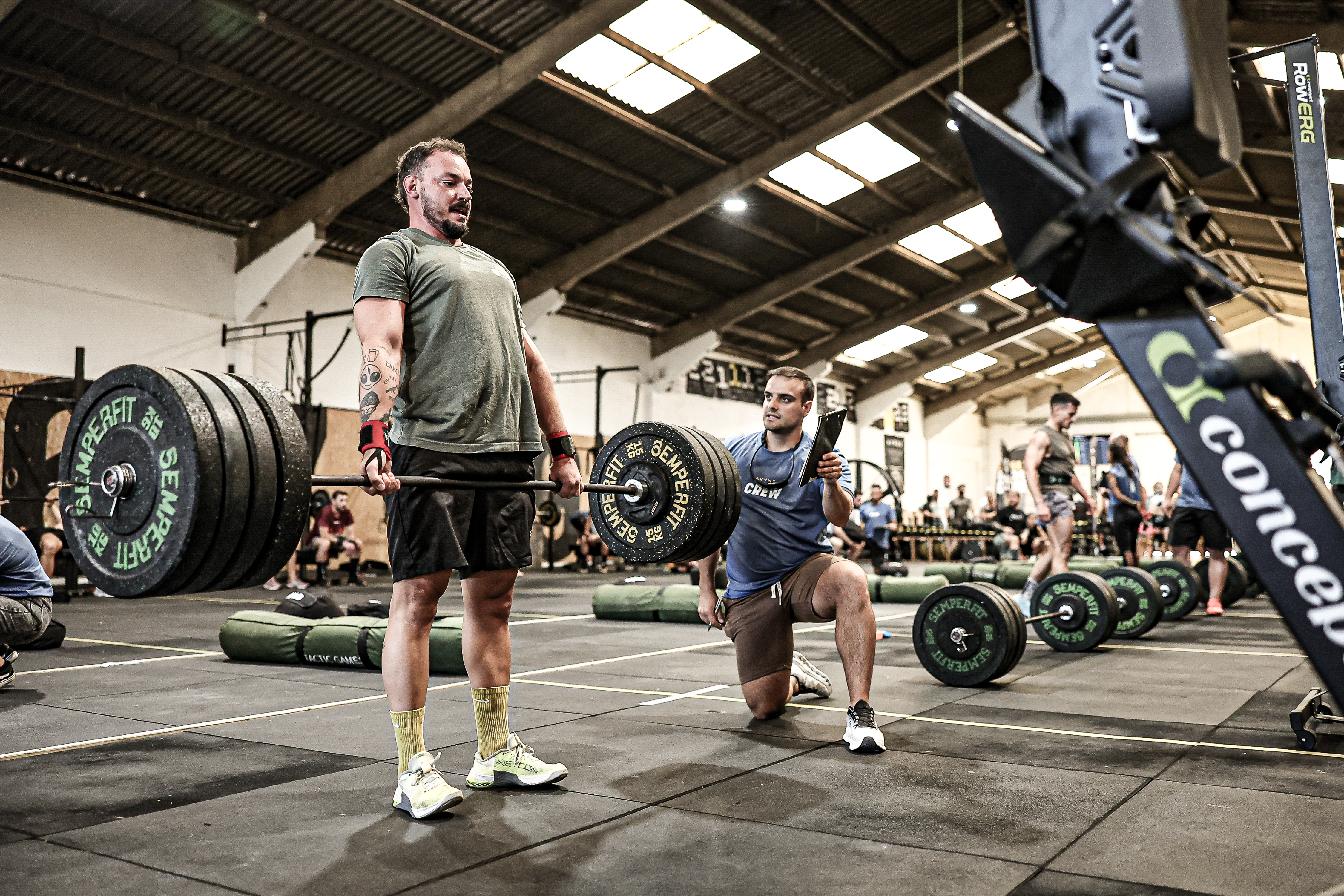 A competitor completes a deadlift beside an event official