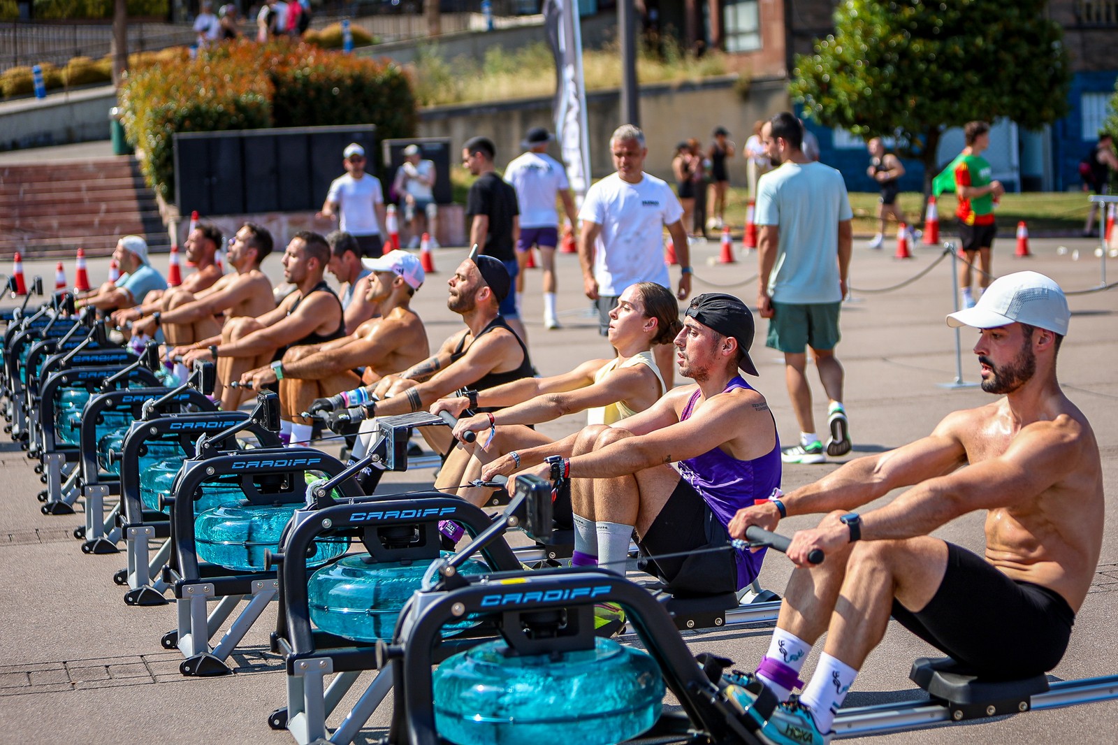 Athletes row on a line of ergometers during the outdoor workout stage of Hurbax Oviedo