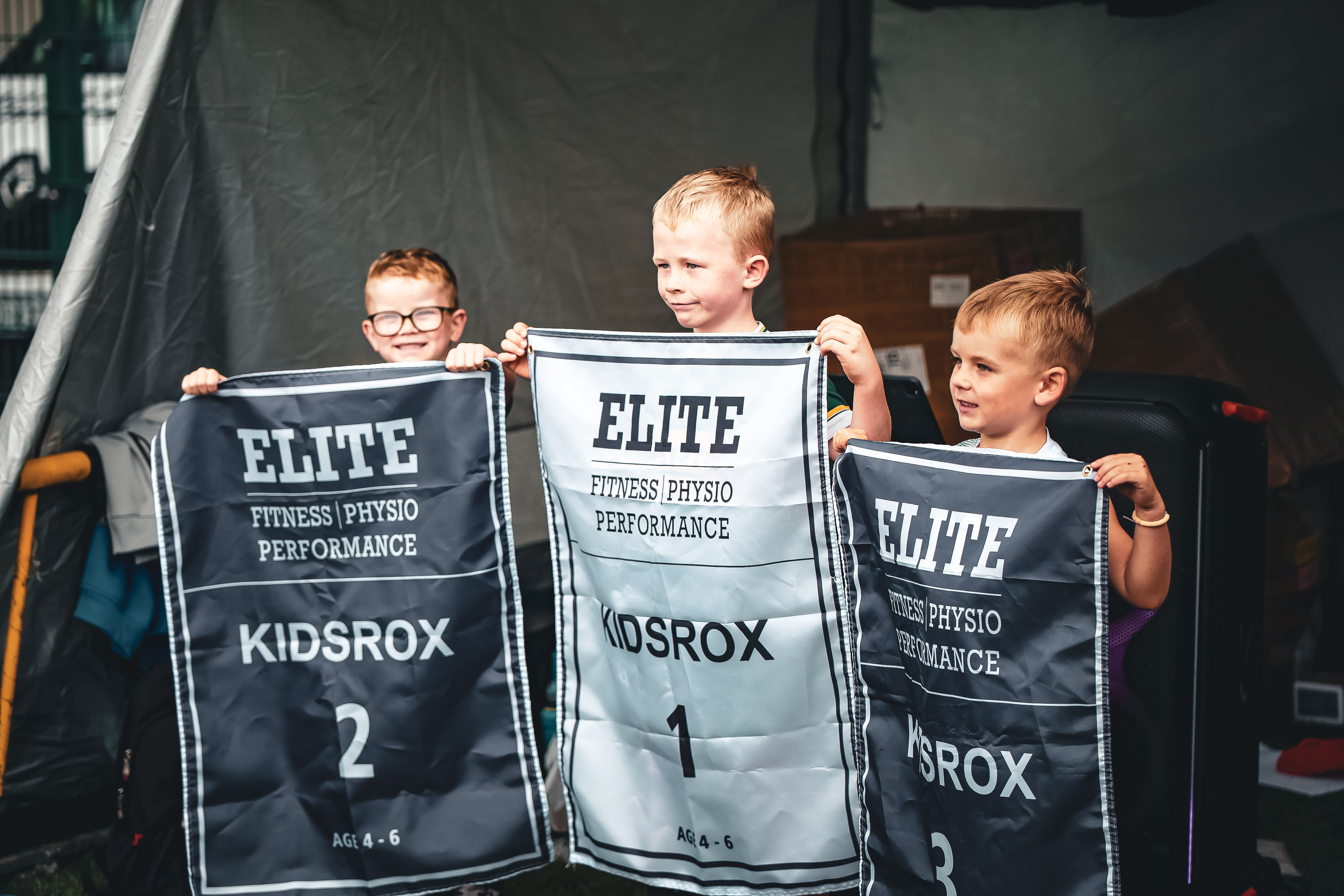 Three young KIDSROX athletes hold first, second and third-place banners in Dublin