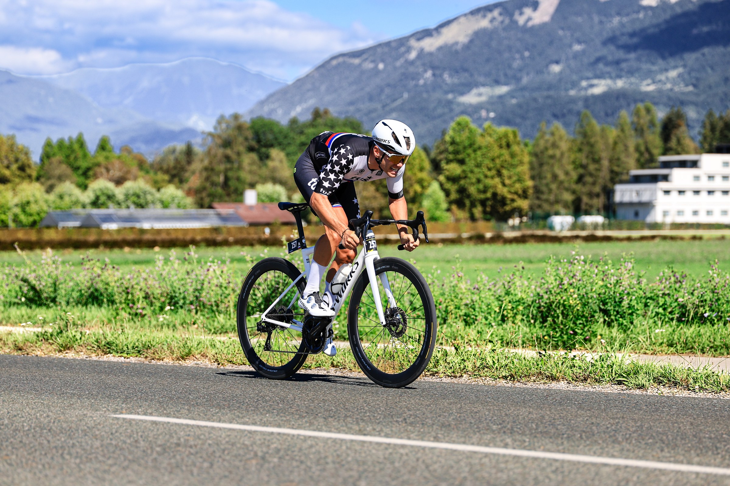 A cyclist races through the Kranj countryside with the Slovenian mountains behind him during L’Étape Slovenia 2026