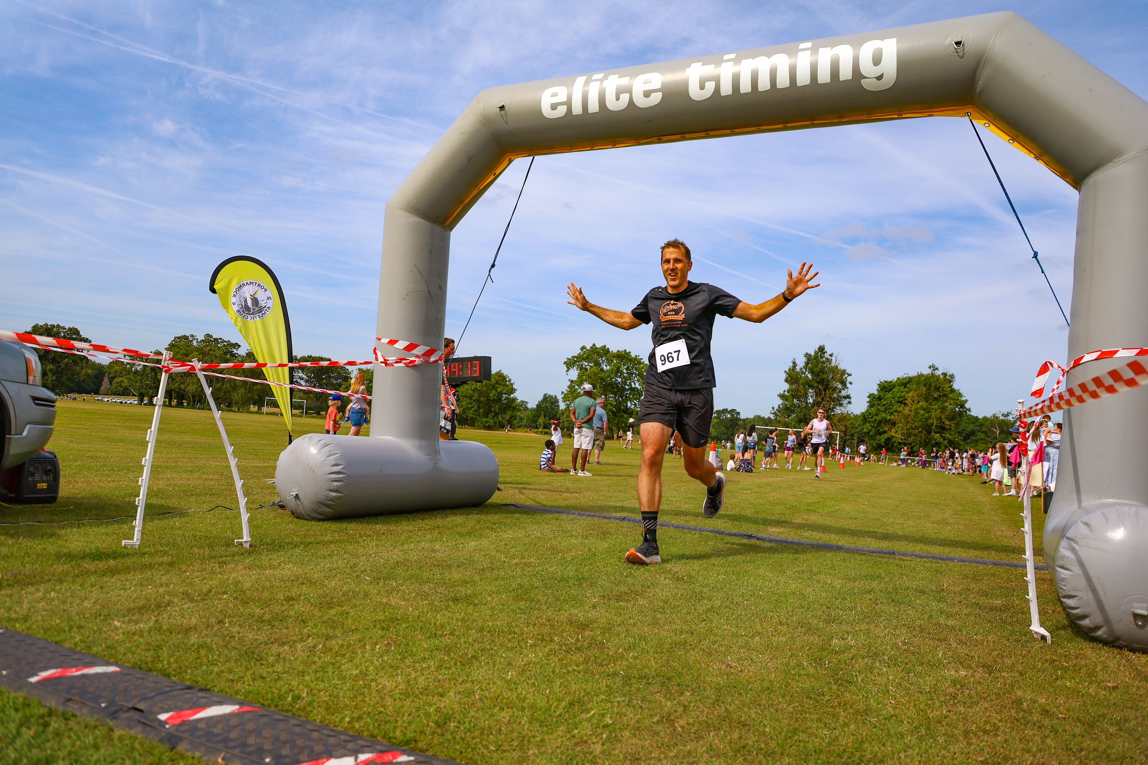 A runner raises his arms in celebration crossing the finish line under the Elite Timing arch at the Malahide Castle 10km