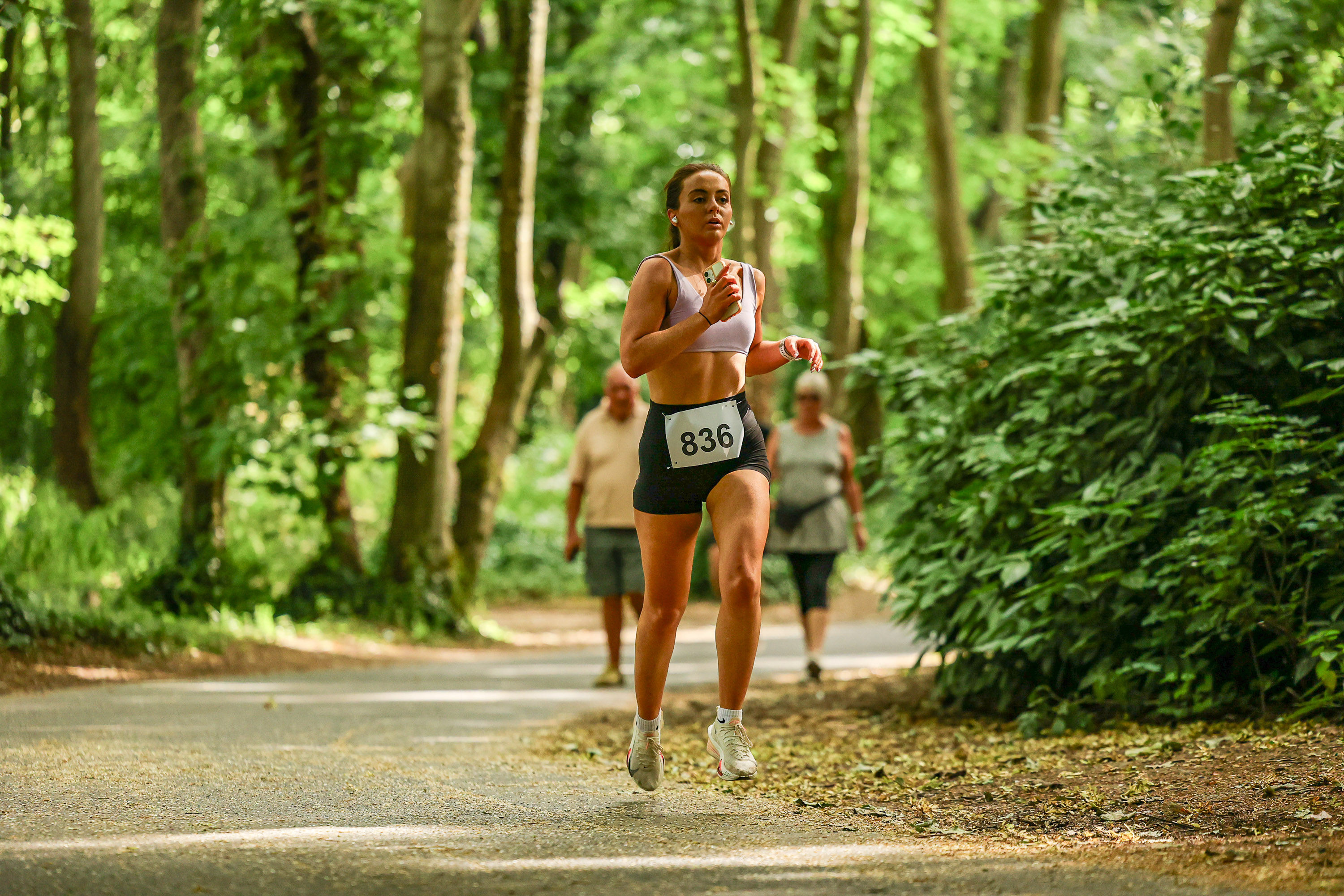 A runner in a lavender sports bra moves along a tree-lined path during the Malahide Castle 10km