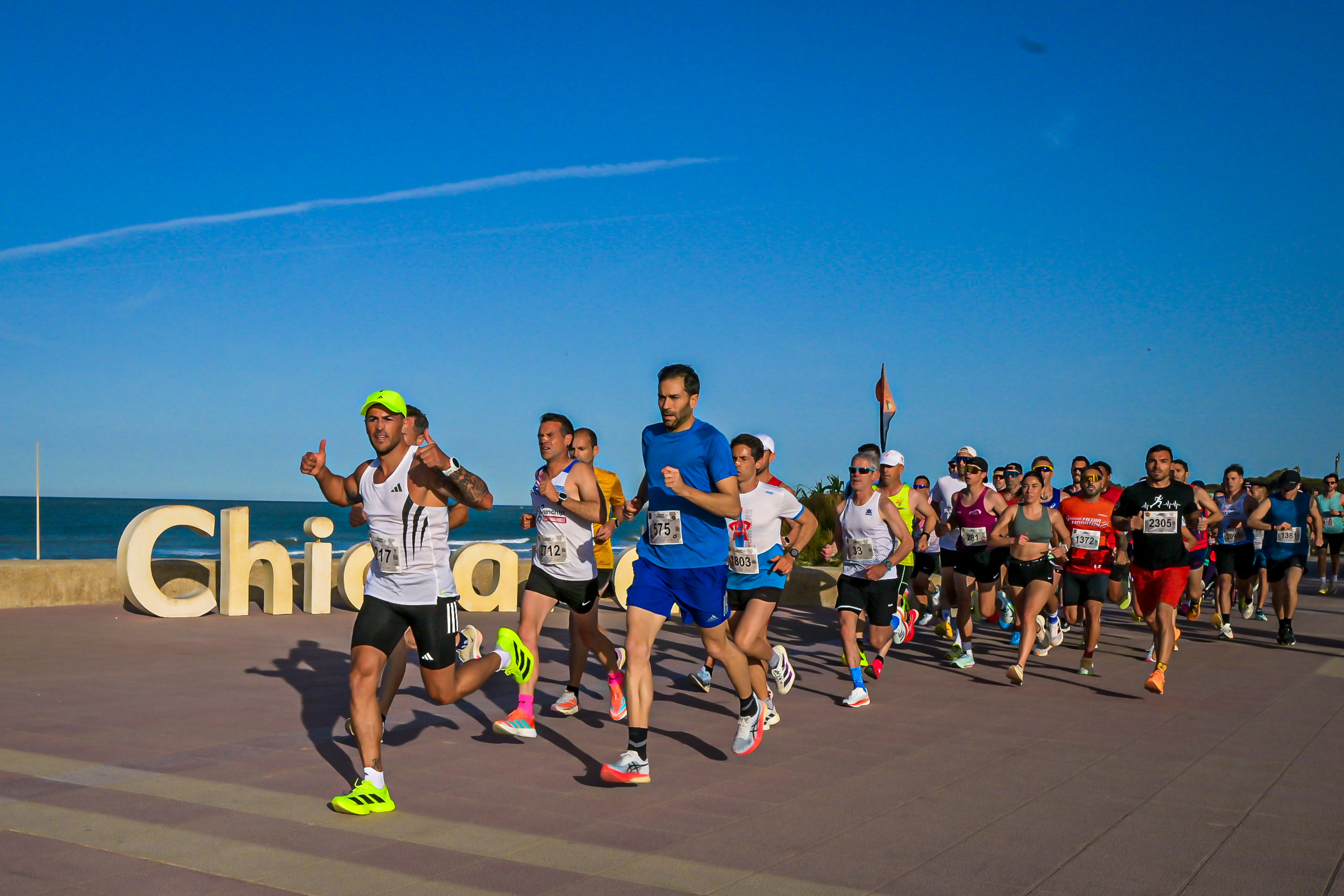 Runners passing the Chiclana seafront sign near the start of the half marathon