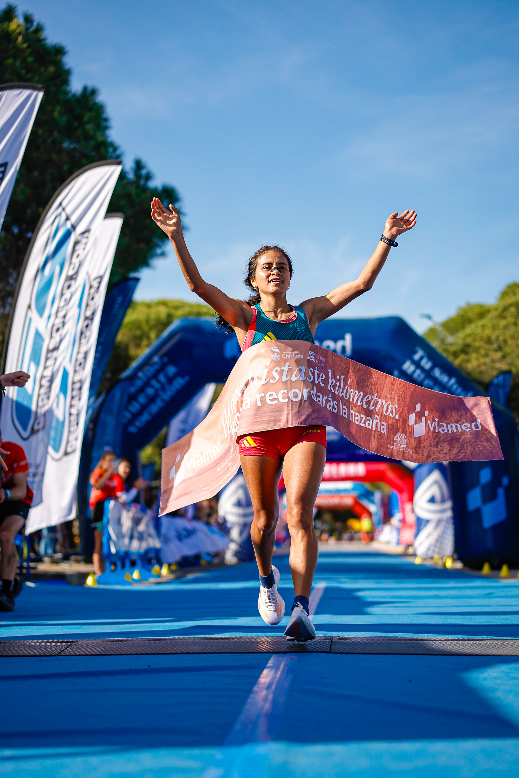 A runner crossing the finish line with the event's Viamed finish tape