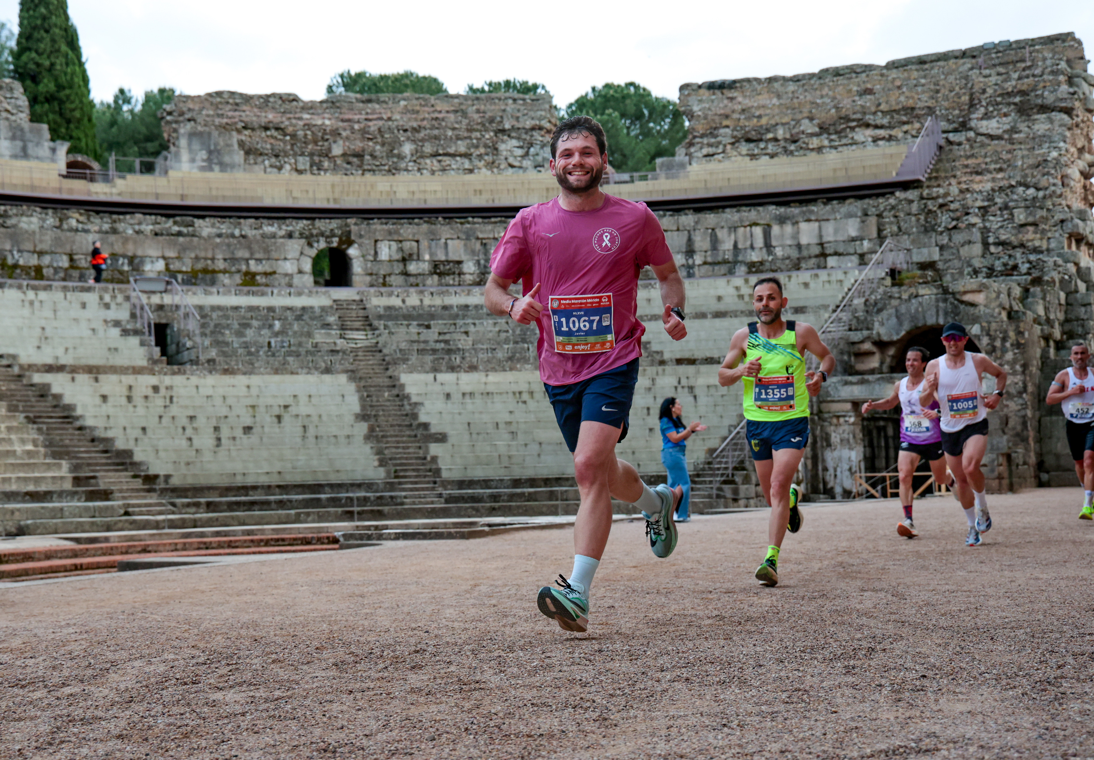 A runner smiling as he passes through the Roman Amphitheatre during the Media Maratón de Mérida