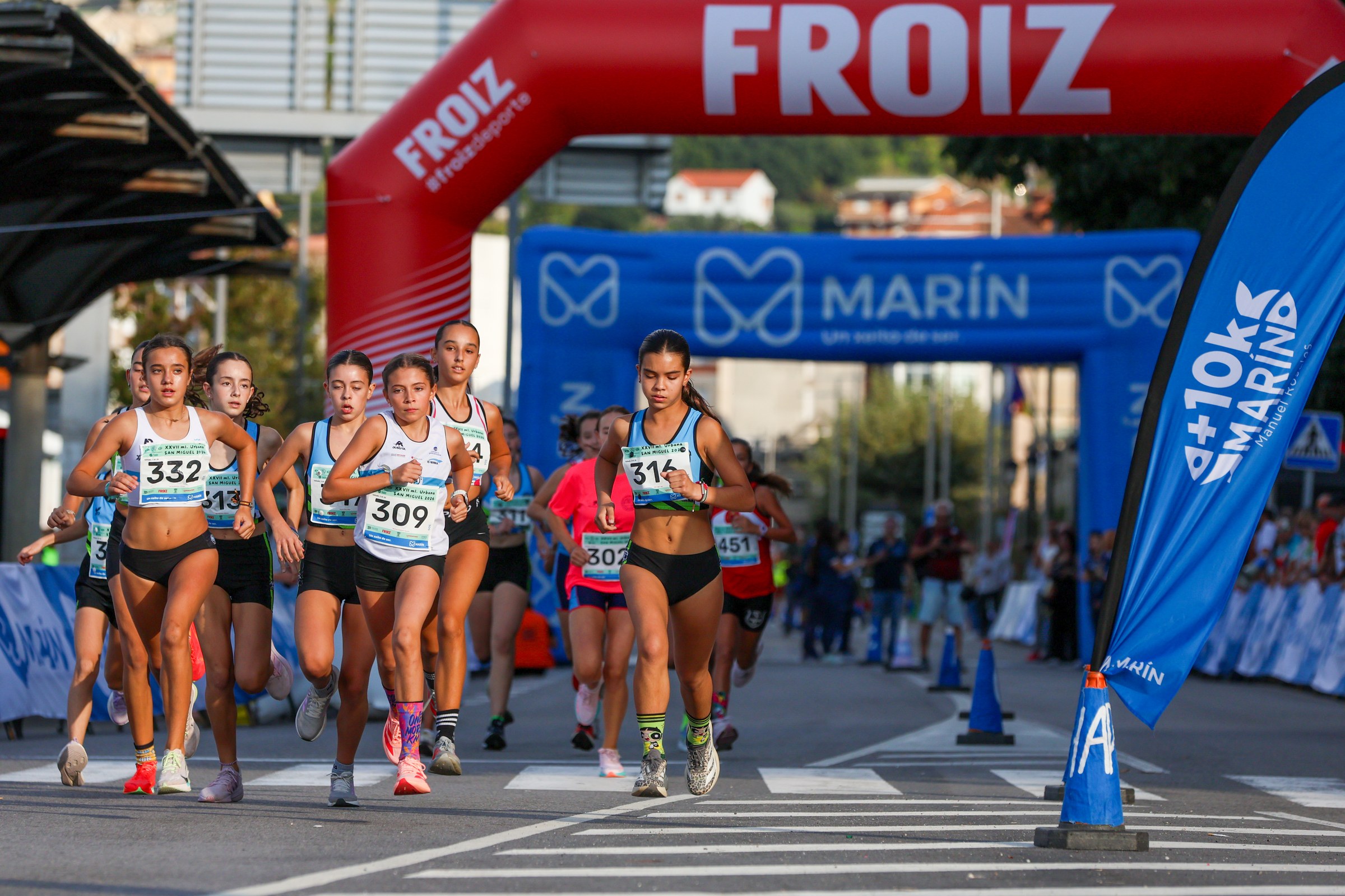 Young runners start a race beneath the event arches in Marín