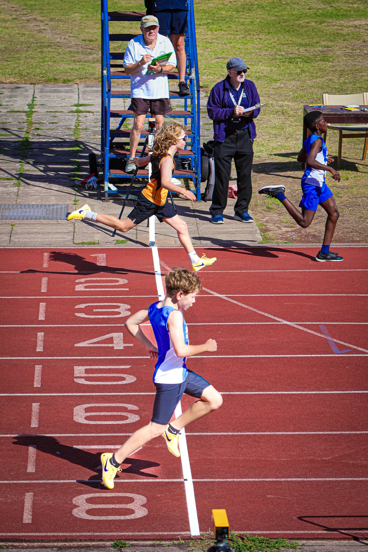 Young athletes race past the finish line as officials record the action at MK Sprint Series 3