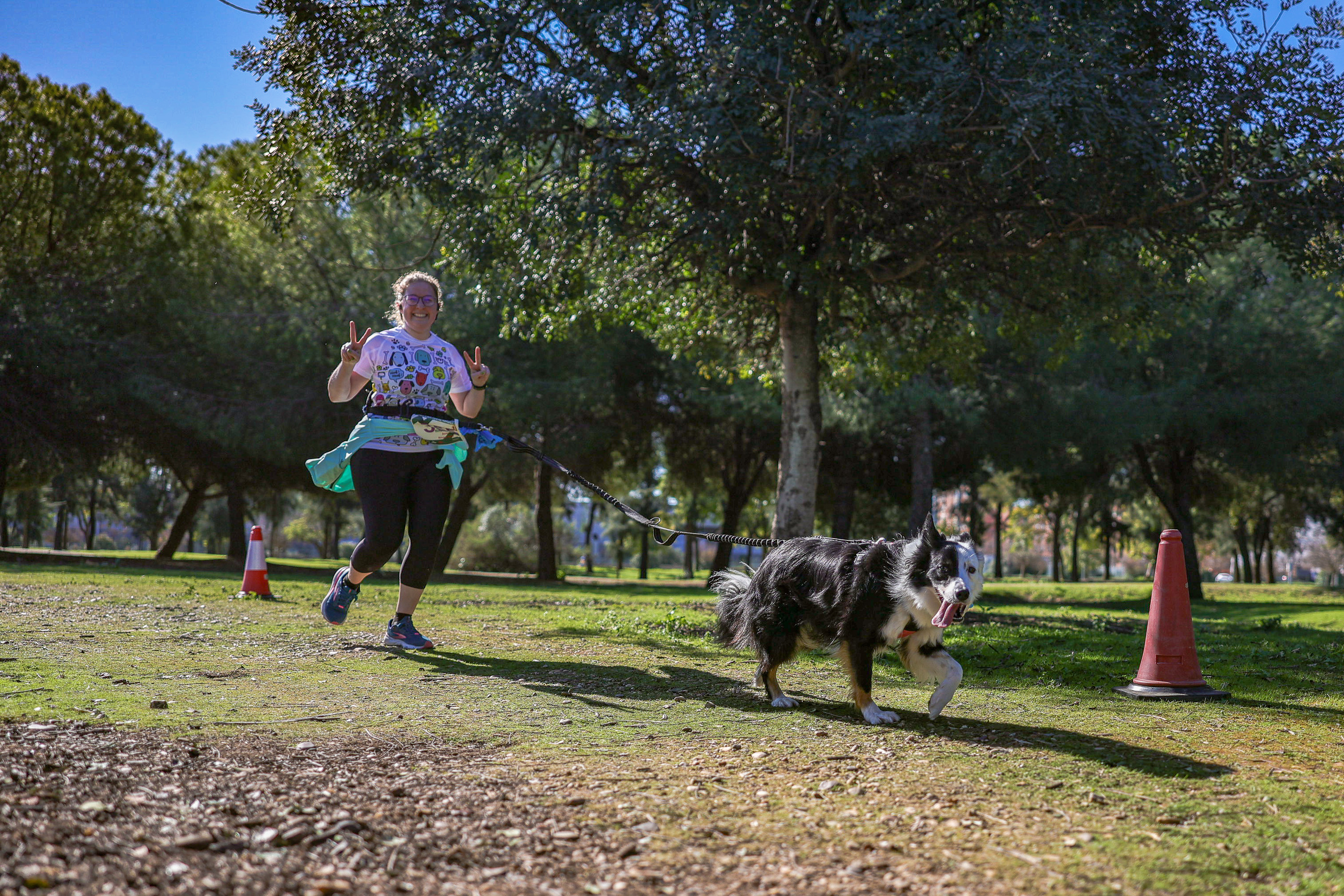 A runner strides through Tamarguillo Park with her dog on a lead during the race