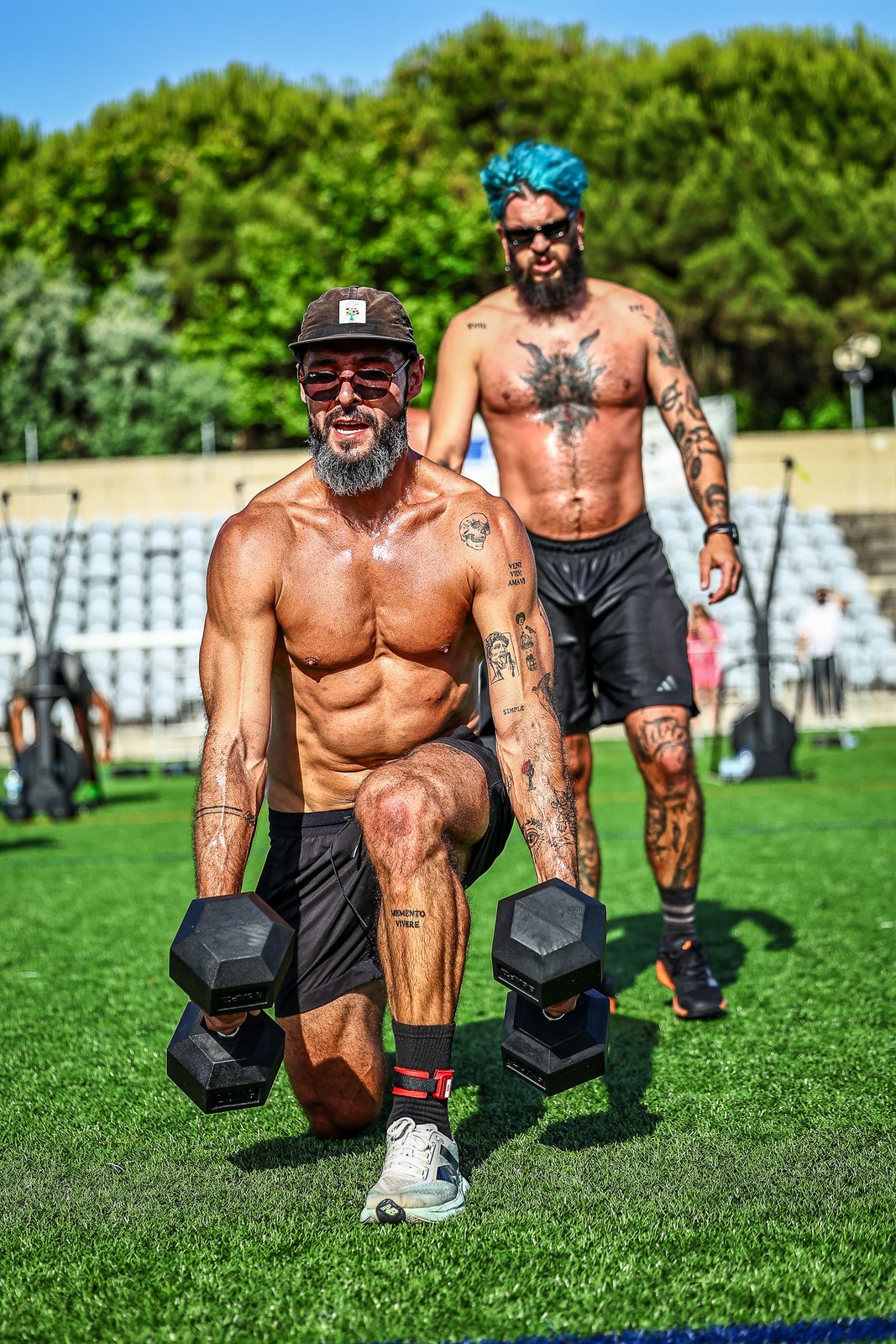 Two athletes carry dumbbells through a lunge station during OVX Games in Oeiras