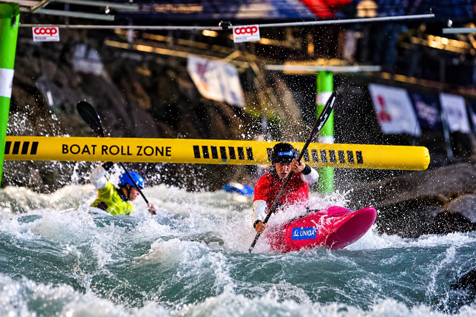 A female canoe slalom athlete drives a pink kayak through heavy whitewater in Ivrea