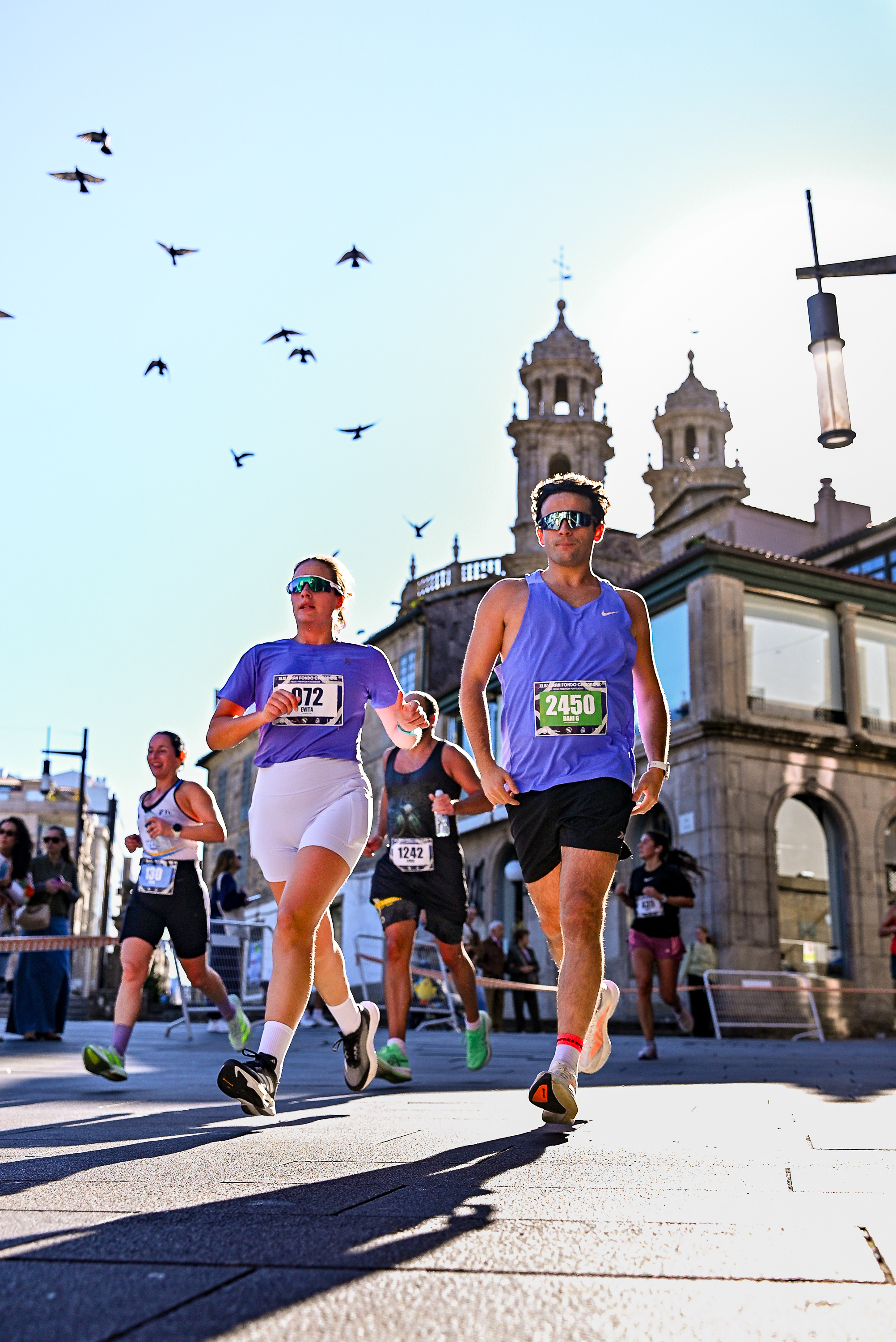 Runners pass stone buildings in Pontevedra