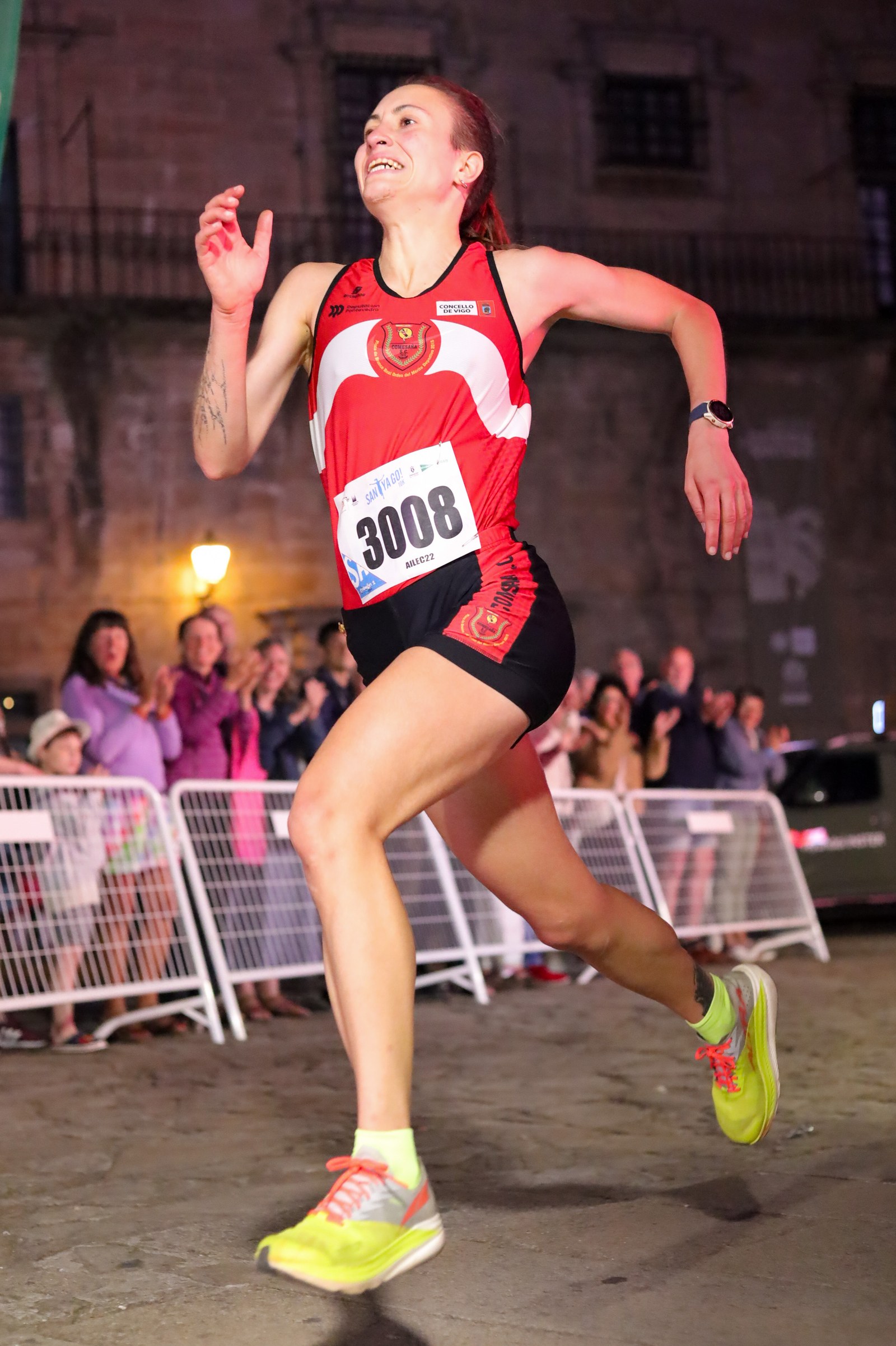 A runner celebrates while sprinting to the finish line at night during the SantYaGo10K in Santiago de Compostela