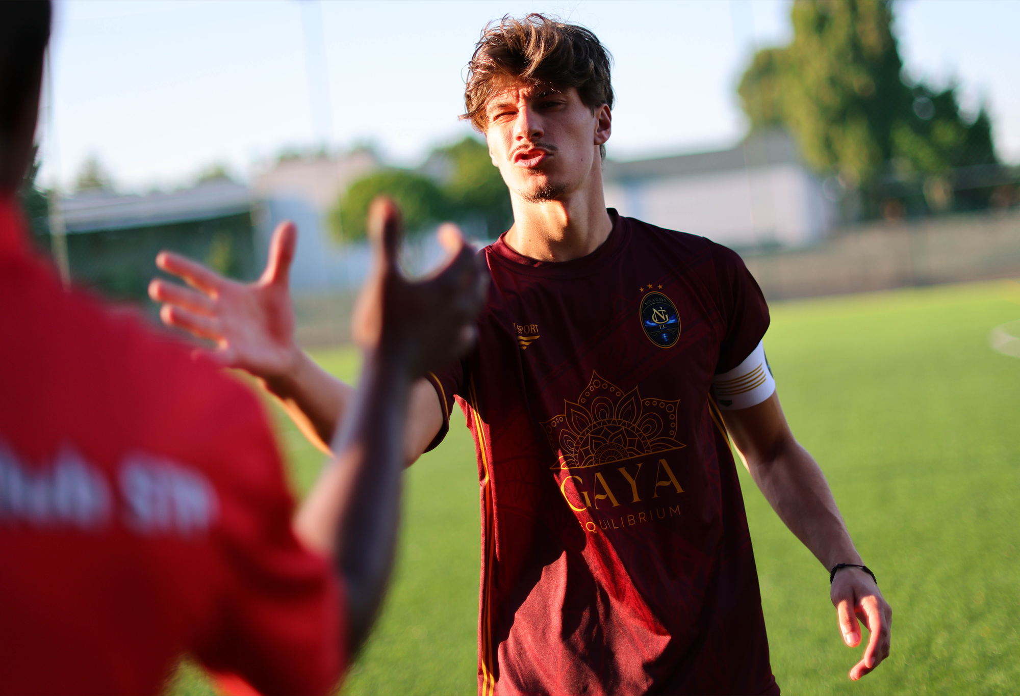 Player wearing a captain’s armband reaches towards another player