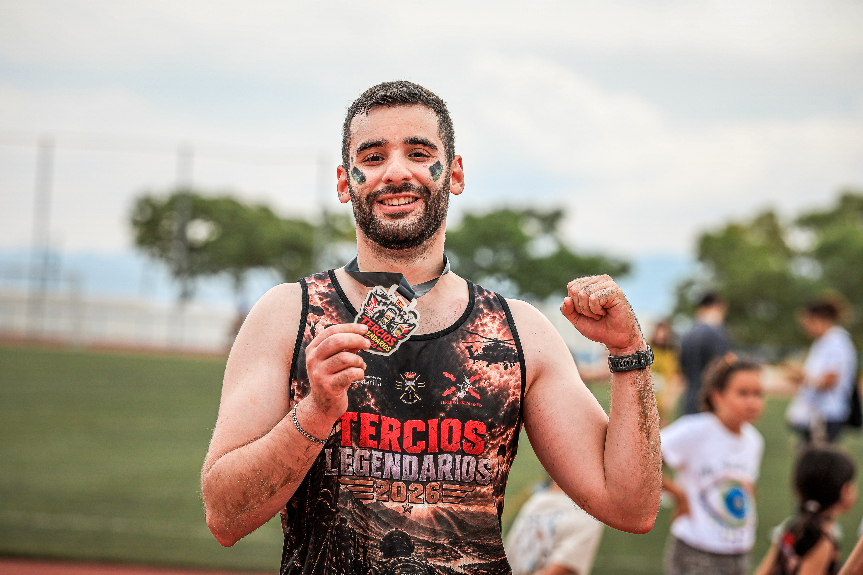 A smiling Tercios Legendarios finisher holds his medal in Alcantarilla