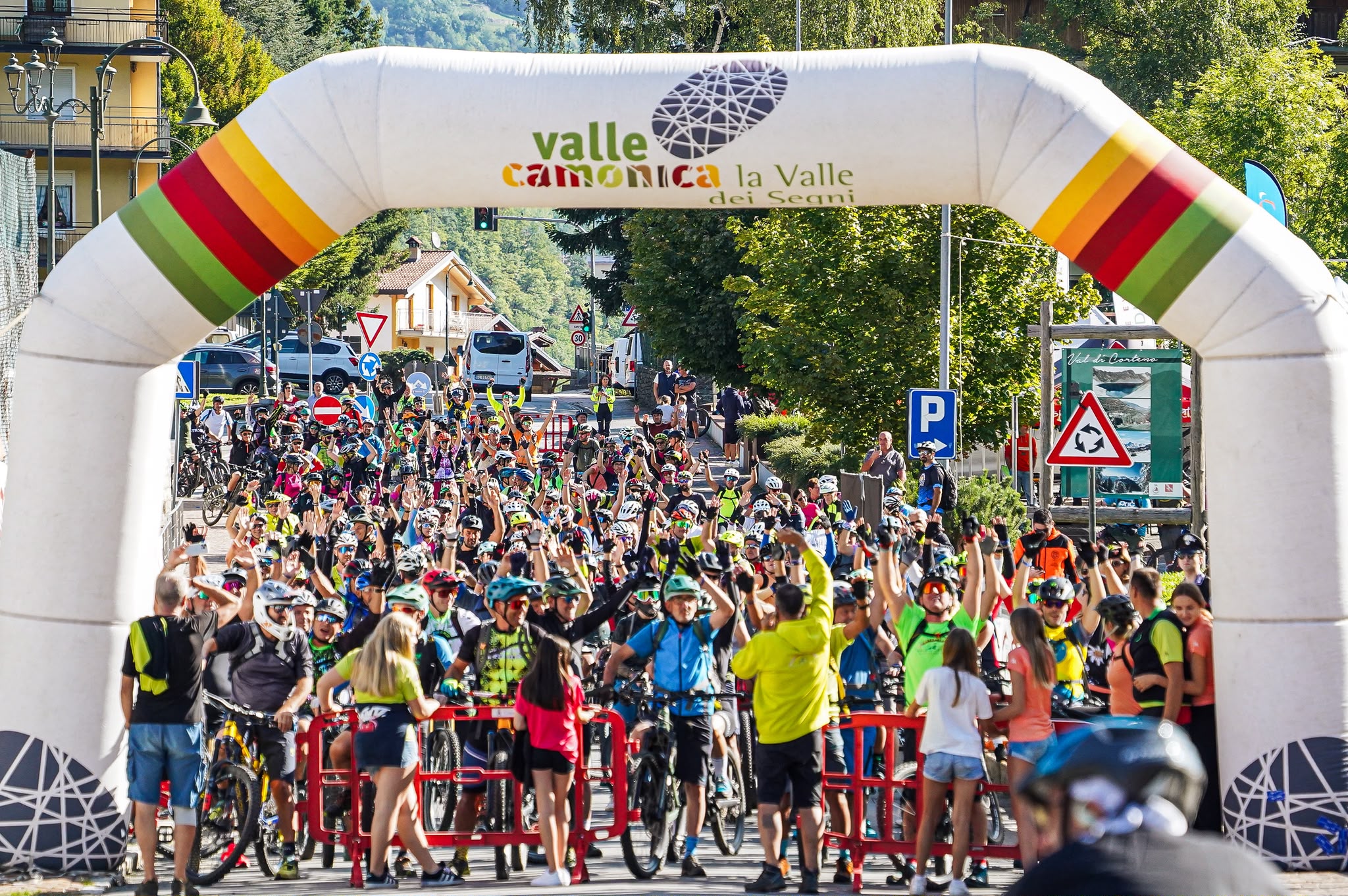 Mountain bikers gather beneath the Valle Camonica start arch in Corteno Golgi