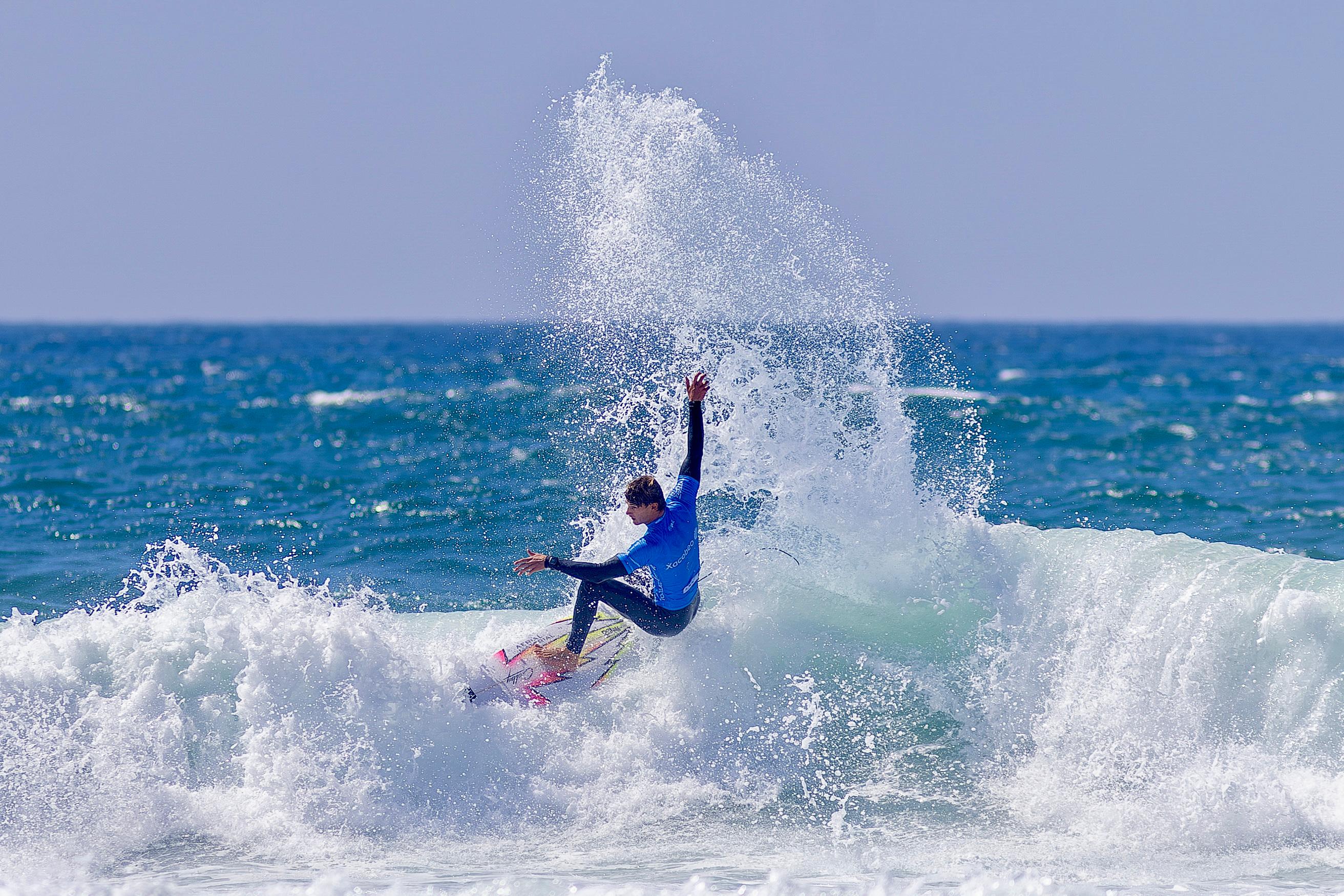 Surfer in a blue jersey throws a column of spray during a turn at Leça da Palmeira