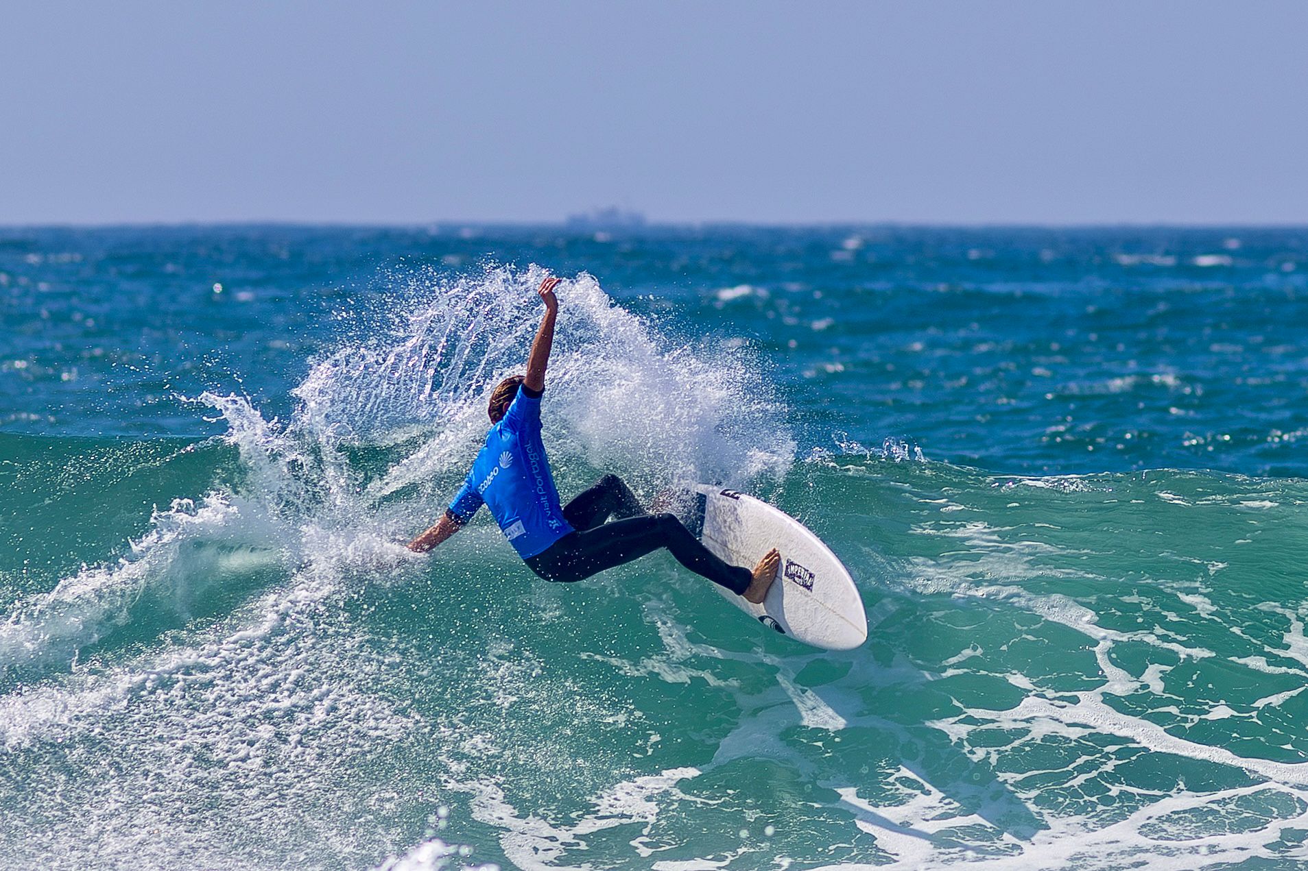 Surfer in a blue competition jersey redirects sharply on a wave at Praia de Leça
