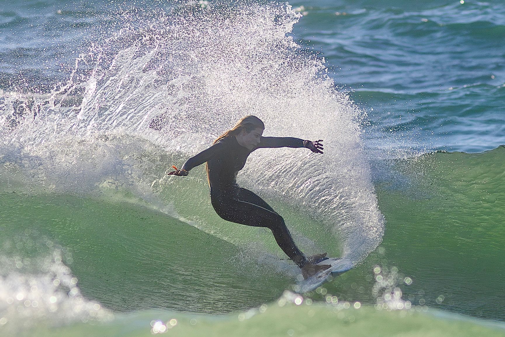 Surfer drives through a cutback as spray arcs above a green wave in Leça da Palmeira